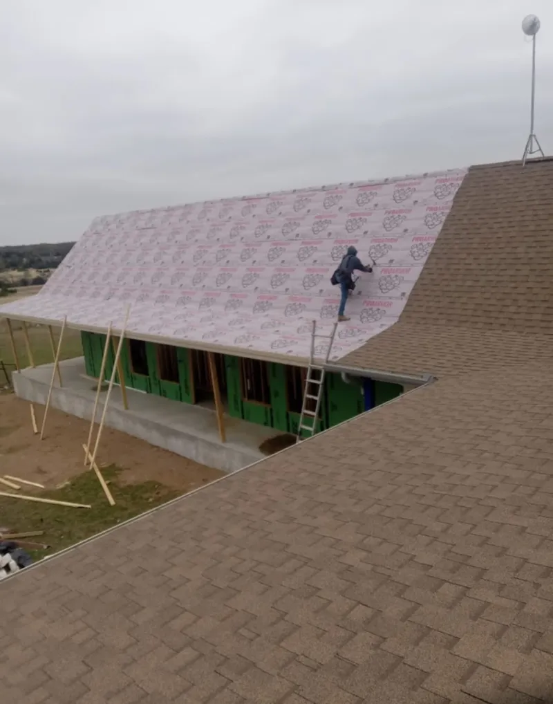 Worker preparing underlayment for a metal roof installation in Summit View